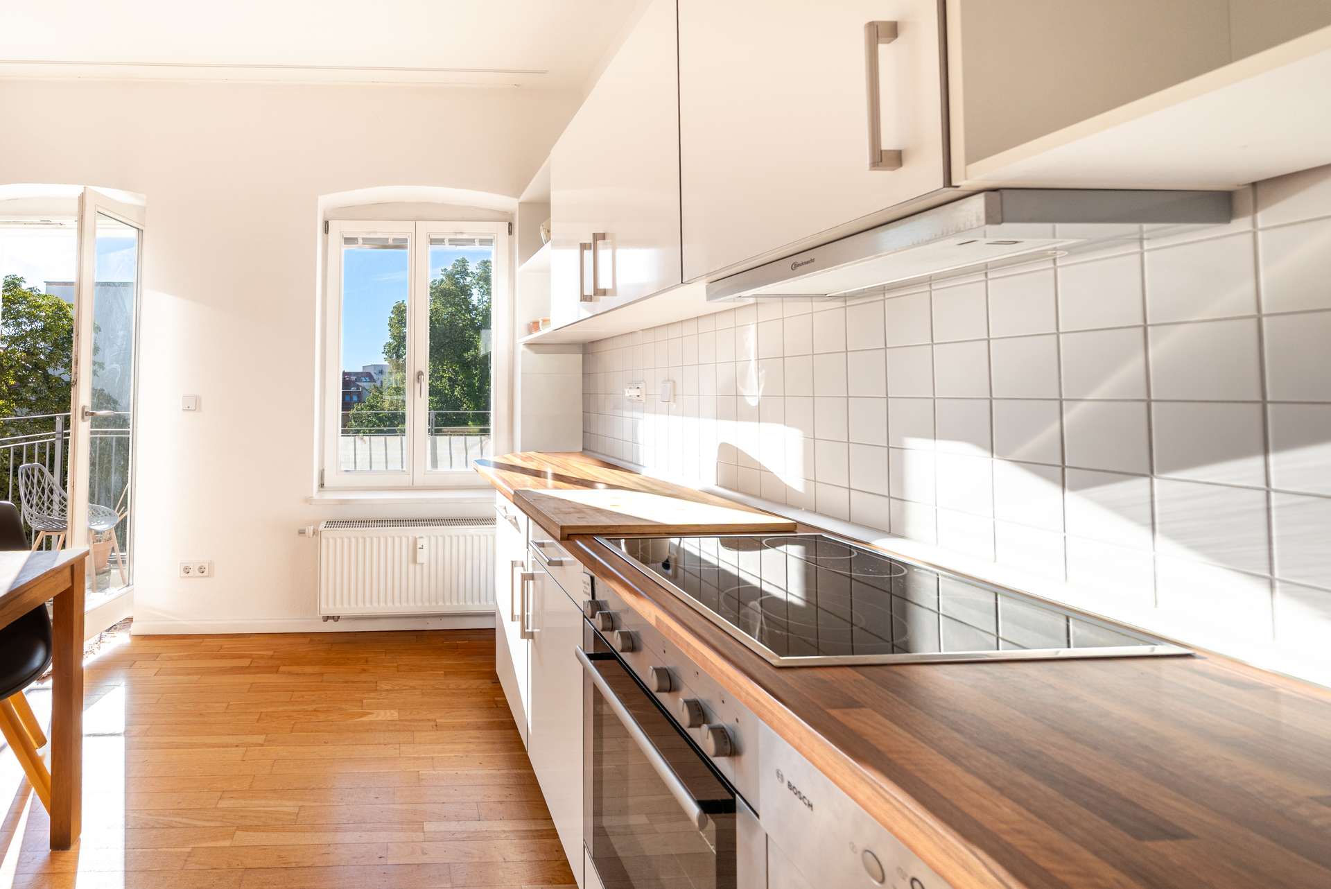 Helle Einbauku00fcche mit Holzarbeitsplatte und Blick ins Gru00fcne