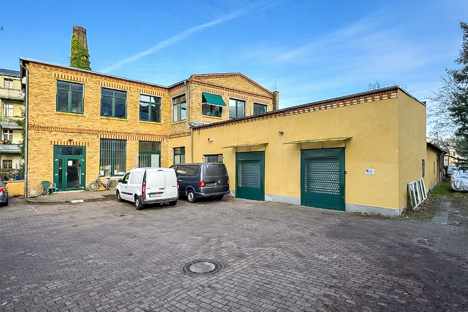 Hof mit rotgelben Ziegelgebäuden und Fahrzeugen